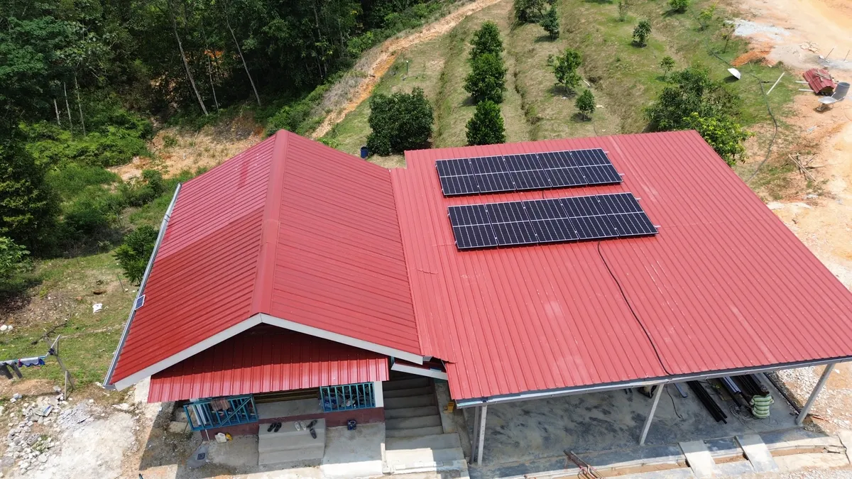 Aerial view of solar panels on the red roof of a hillside house