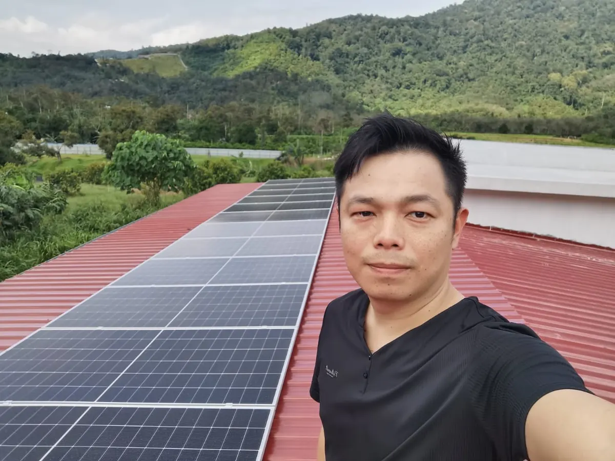 Jomsolar team member beside the solar array on a red roof
