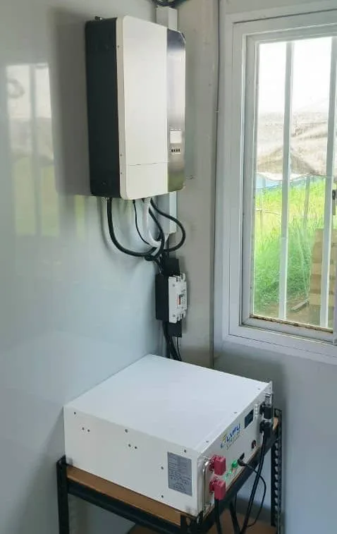 Wall-mounted off-grid inverter above a battery unit beside a window