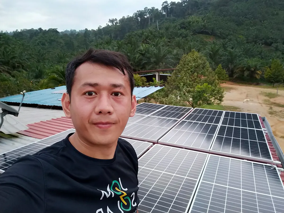Jomsolar team member in front of a rooftop solar array in the hills