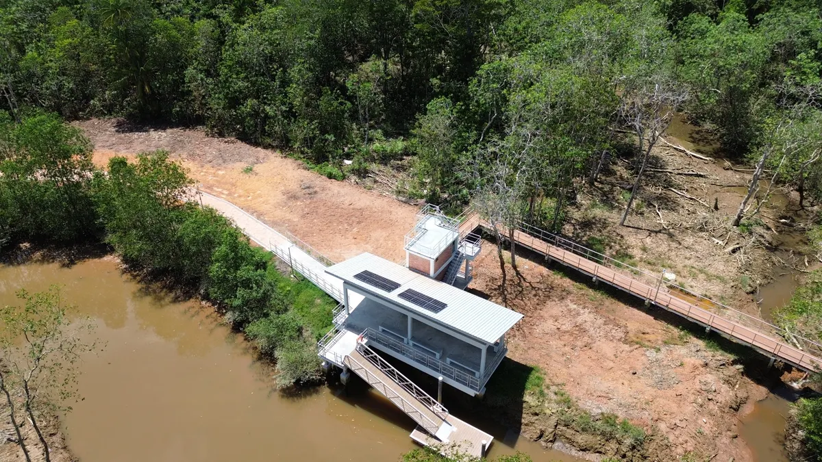 Aerial view of a small riverside building with solar panels and a boardwalk