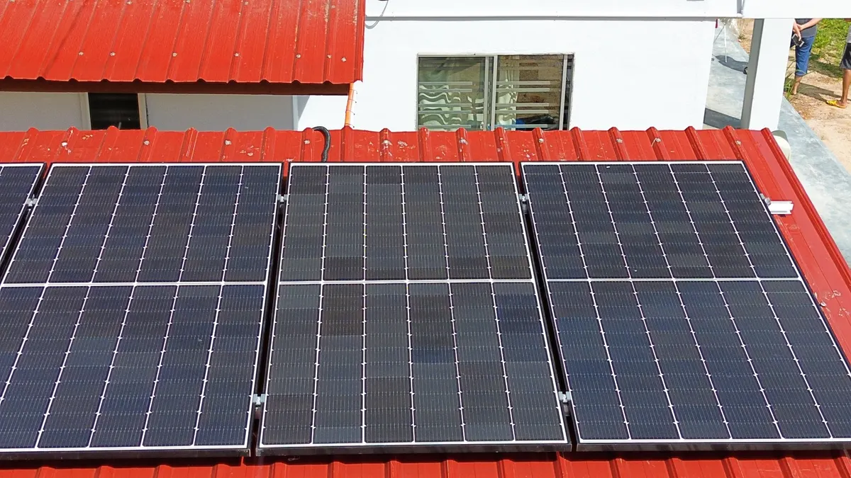 Close-up of rooftop solar modules on a red-roofed building