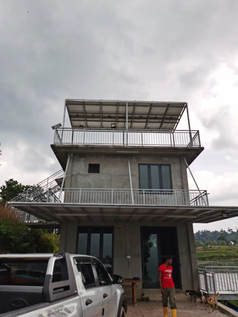 Three-storey concrete house with a solar array on its rooftop frame
