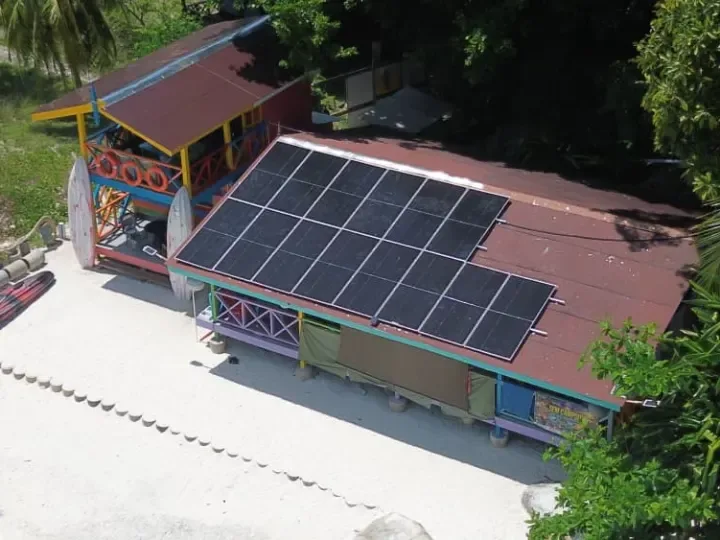 Aerial view of a solar array on the roof of a beachside building at an island camp on Pulau Lang Tengah